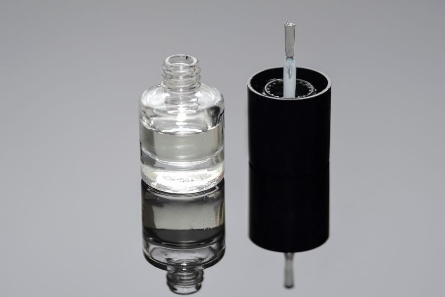 Clear nail polish bottle on reflected background